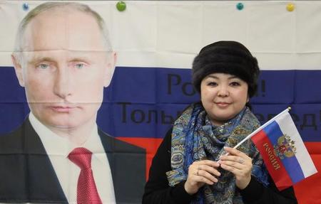 プーチン（の旗）と一緒に参加を呼び掛ける古池麻衣子さん＝神戸市内