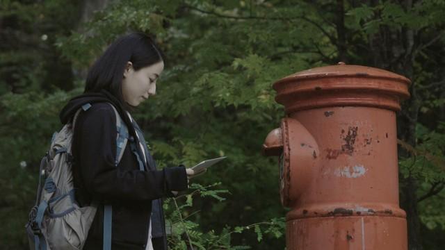 映画「漂流ポスト」のワンシーン。ポストの前で手紙を手にする主役の雪中梨世 (Ｃ) Kento Shimizu
