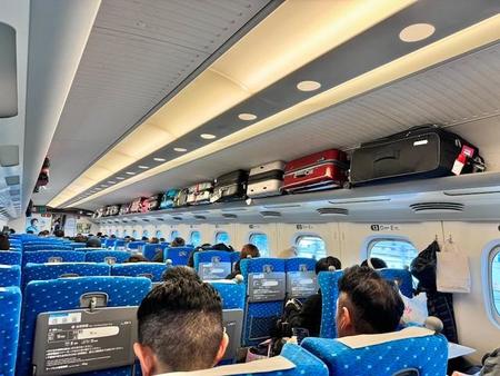 東海道新幹線の棚の上がカオス…。右側の棚は訪日客のスーツケースでいっぱい。左側の棚からは、持ち込み予約が必要な特大荷物がはみ出している危険な状況（画像提供：yukapoさん @yukapova）