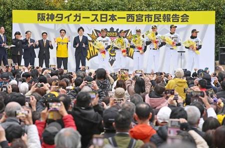 壇上で日本一を報告する阪神タイガースの選手らに向かって六甲おろしを合唱するファンたち