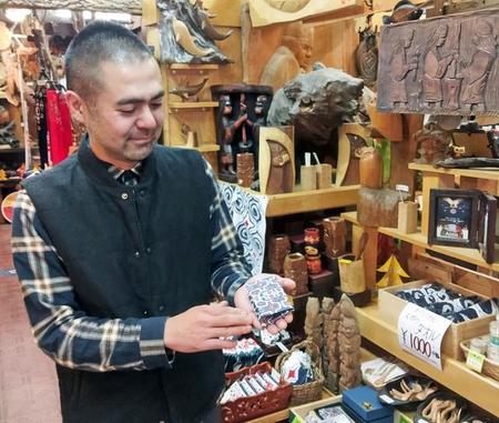 自身がデザインしたアイヌ文様の商品を手にする藤戸さん（北海道釧路市）＝あらいそ提供
