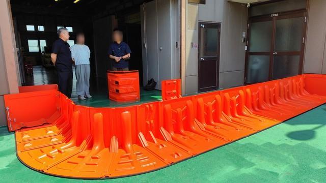 置いて繋ぐだけで設置できる止水板「Flood Guard F」（左端の人物が藤井社長）