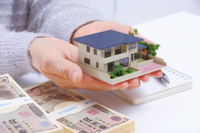 住宅とお金とシニア女性の手元※画像はイメージです（琢也 栂/stock.adobe.com）