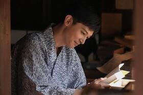 ヘブンの最新作『東の国から』の冒頭に、自分に向けられた献辞を見つけて微笑む錦織（吉沢亮）　(C)NHK