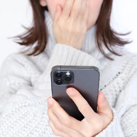 携帯を見て驚く女性　※画像はイメージです（webbiz/stock.adobe.com）