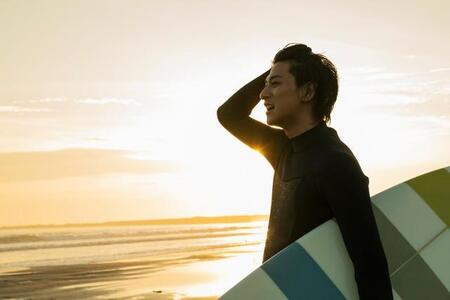 海でサーフィンをする男性※画像はイメージです（One/stock.adobe.com）