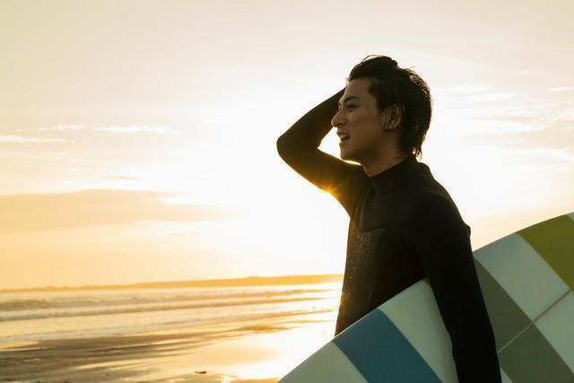 海でサーフィンをする男性※画像はイメージです（One/stock.adobe.com）