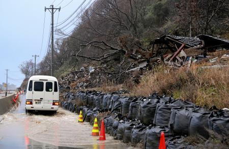 　土砂崩れに巻き込まれ、土のうにとどめられたまま残る建物。道路は雨で冠水していた＝１５日午後、石川県珠洲市