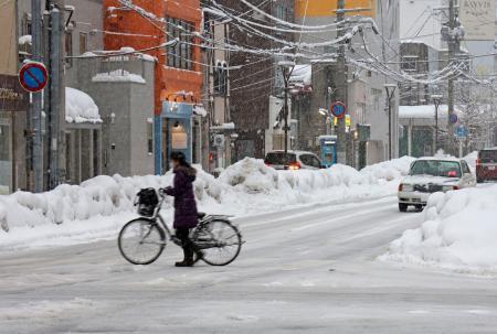 　雪が降る青森市で自転車を押す人＝２２日午後