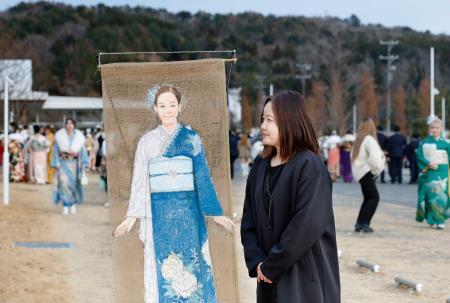 　宮城県石巻市の成人式会場で、麻布に描かれた振り袖姿の長女愛梨ちゃんの絵を見つめる佐藤美香さん＝１２日午後