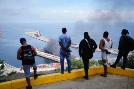 　ベネズエラの首都カラカス近郊の港で爆発の後、上る黒煙を眺める人たち＝３日（ＡＰ＝共同）