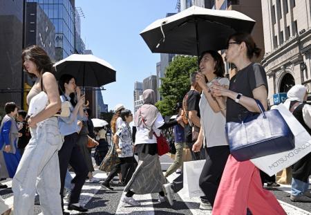 　日傘を差して東京・銀座を歩く人たち。都心は今年初の真夏日となった＝１７日