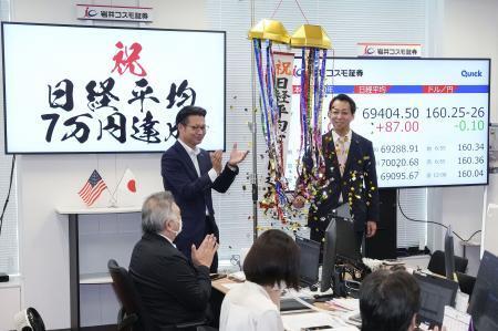 　日経平均株価が取引時間中に初めて７万円を超え、くす玉を割って祝福する岩井コスモ証券の社員ら＝１６日午後、東京都中央区