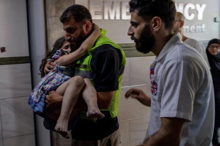 　２０日、レバノン南部の病院で、イスラエルによる攻撃で負傷した少女を搬送する人（ロイター＝共同）