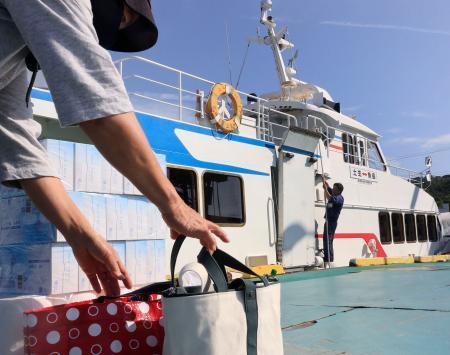 　魚島に向かう船に生活用品を積み込む利用客＝５月、愛媛県上島町の弓削港
