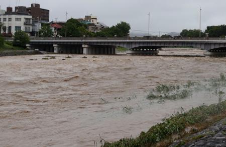 　大雨で増水し、激しく流れる鴨川。奥は賀茂大橋＝２６日午前９時４分、京都市左京区