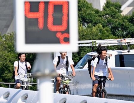 　酷暑日となった愛知県豊田市で自転車に乗る人たち。街頭温度計は気温４０度を示していた＝２３日午後