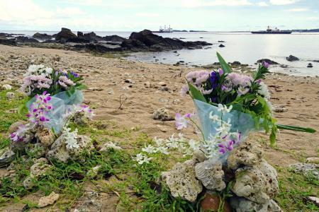 　転覆事故の現場海域を臨む浜辺に手向けられた花束＝１６日午後、沖縄県名護市