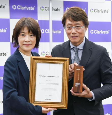 　クラリベイト関係者から賞状とトロフィーを受け取った九州大の安達千波矢主幹教授（右）＝１７日午後、東京都港区
