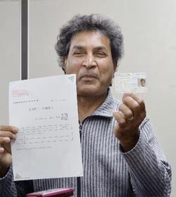 　「在留特別許可」が与えられ、公布された在留カード（右）を手にするパキスタン人男性＝２３日午前、東京・霞が関の司法記者クラブ