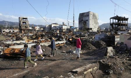 　地震による大規模火災でほぼ全域が焼失した「輪島朝市」周辺を歩く家族連れ＝４月１日、石川県輪島市