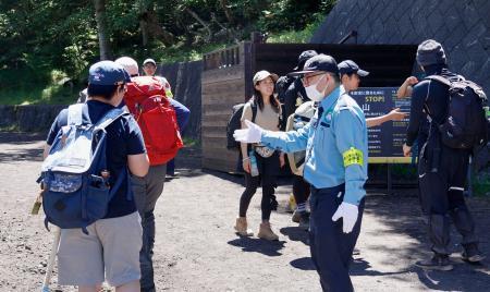 　富士山の山梨県側登山道「吉田ルート」の５合目でゲートを通過する登山客（左）＝１１日