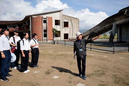 　震災遺構・大川小を視察する輪島高の生徒らと案内する三條すみゑさん（右端）＝２７日午前、宮城県石巻市