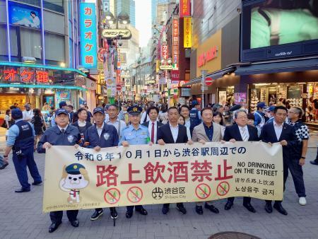 　「路上飲酒禁止」と書かれた横断幕を持って練り歩く東京都渋谷区長の長谷部健氏（中央）ら＝１日午後、東京都渋谷区