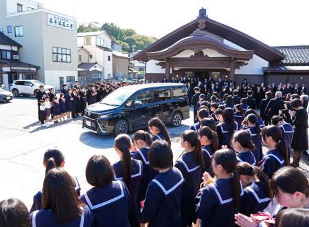 　喜三翼音さんの父鷹也さんらを乗せ、葬儀会場を出る車を見送る多くの参列者＝１２日午前、石川県輪島市