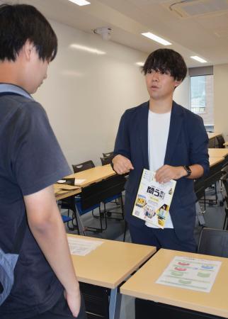 　学生に不在者投票のやり方を説明する、学生団体代表の藤田星流さん（右）＝１６日、東京都文京区の中央大茗荷谷キャンパス