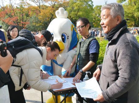 　広島市の平和記念公園で署名する外国人観光客＝２２日午後