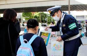 　歩行者に反射材を配り、夕暮れ時や夜間の外出時の着用を呼びかける警視庁の警察官＝１日午後、東京都渋谷区