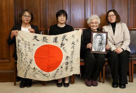 　戦死した天川清三郎さんの寄せ書き入り日章旗を受け取った畑中綾子さん（右から２人目）と親族＝５日、京都市役所