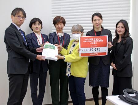 　スポーツ庁の担当者（左端）に「歯止め規定」撤廃を求める署名を手渡す団体のメンバーら＝２７日午後、文科省