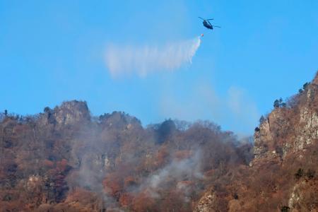 　群馬県富岡市の妙義山で消火活動するヘリコプター＝９日午前８時３１分