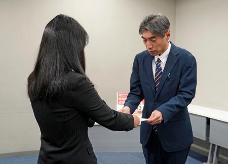 　法務省の担当者（右）に嘆願書を手渡す小関孝徳さんの母代里子さん＝９日午後、東京都千代田区