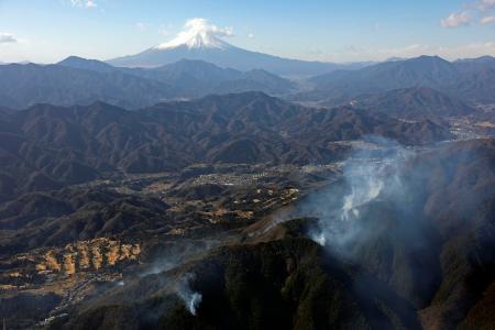 　延焼が続く山梨県上野原市の扇山（手前）。奥は富士山＝１１日午前１０時２５分（共同通信社ヘリから）