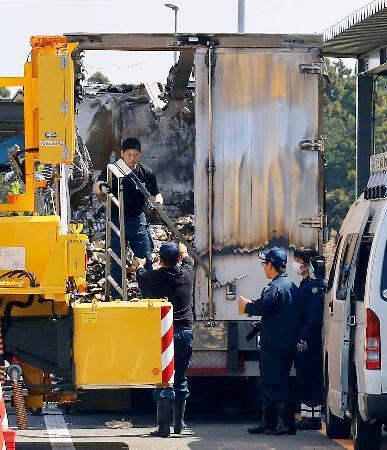 　炎上した大型トラックを調べる三重県警の捜査員ら＝３日午前、三重県菰野町