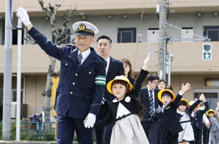 　新１年生と手をつないで横断歩道を渡る警視庁の筒井洋樹警視総監（手前左）＝６日午後、東京都大田区