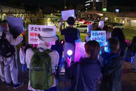 　戦争反対などを訴えるポスターを手にした参加者＝８日、茨城県つくば市