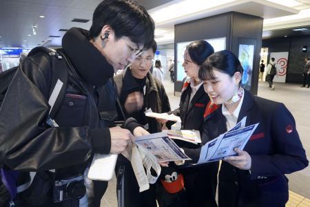 　モバイルバッテリーの取り扱い変更を利用客にチラシで周知する航空会社の関係者＝４月、羽田空港
