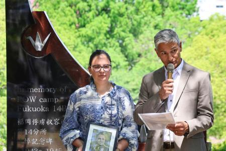 　外国人捕虜の追悼式でスピーチする遺族のクイントゥス・ファンデルベイルさん。左は娘のリサさん＝１０日午前、長崎市