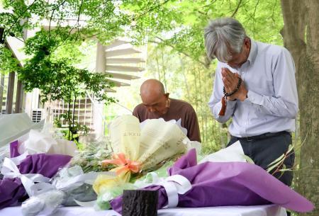　空自機墜落事故から１年となり、献花台の前で手を合わせる人たち＝１４日午後、愛知県犬山市