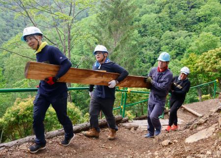 　日航ジャンボ機墜落事故から４１年となるのを前に、登山道整備に使う丸太を運ぶ群馬県警藤岡署の有志署員＝１３日午前、群馬県上野村
