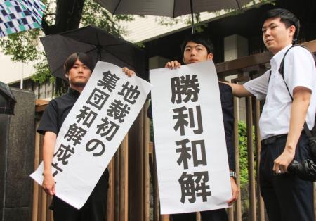 　建設石綿訴訟の和解成立後、「勝利和解」などと書かれた紙を掲げる弁護団＝２６日午後、東京地裁前