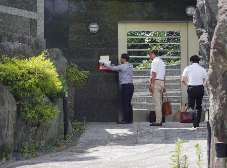 　野村悟被告の自宅周辺に貼られた事務所使用制限の標章を剥がす福岡県警の捜査員ら＝１６日午後、北九州市小倉北区