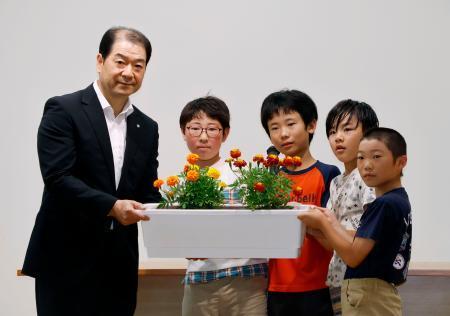 　群馬県上野村の村立上野小で、黒沢八郎村長（左端）にマリーゴールドを引き渡す児童たち＝１７日午前