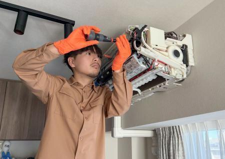 　エアコンの清掃をするＮＰＯ法人「サンカクシャ」スタッフの中嶋直人さん＝２０２５年１２月
