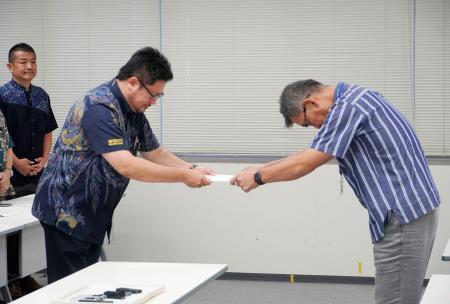 　防衛省沖縄防衛局の村井勝局長（右）に意見書を手渡す沖縄県議会・米軍基地関係特別委の小渡良太郎委員長＝２３日午前、沖縄県嘉手納町