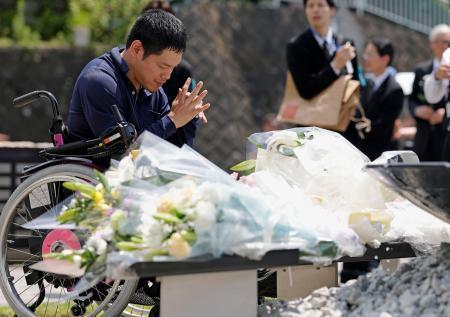 　津久井やまゆり園の「鎮魂のモニュメント」に献花し、手を合わせる男性＝２６日午前、相模原市